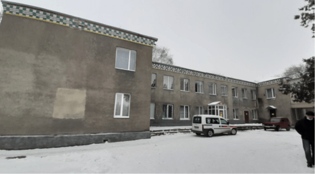 Building in Ukraine with snow and a vehicle in the foreground.